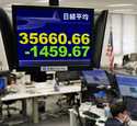A currency trader works under an electronic stock board at a foreign currency trading firm in Tokyo…
