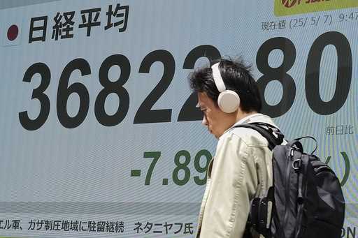 A person walks in front of an electronic stock board showing Japan's Nikkei index at a securities f…