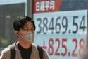 A person walks in front of an electronic stock board showing Japan's Nikkei index at a securities f…