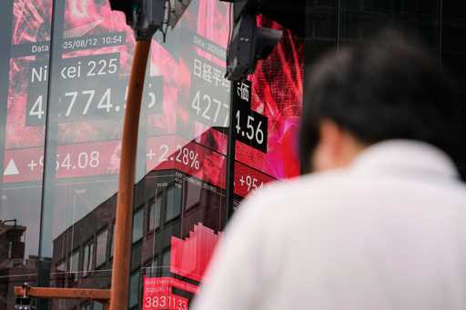 A person stands in front of an electronic stock board showing Japan's Nikkei index at a securities …