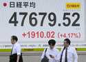 People stand in front of an electronic stock board showing Japan's Nikkei 225 index at a securities…