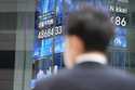A person stands in front of an electronic stock board showing Japan's Nikkei index at a securities …
