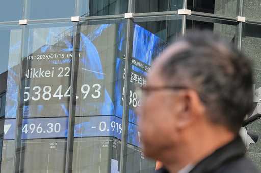 A person walks in front of an electronic stock board showing Japan's Nikkei index at a securities f…