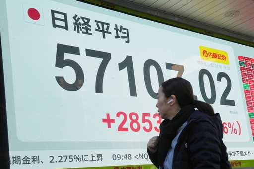 A person walks in front of an electronic stock board showing Japan's Nikkei index at a securities f…