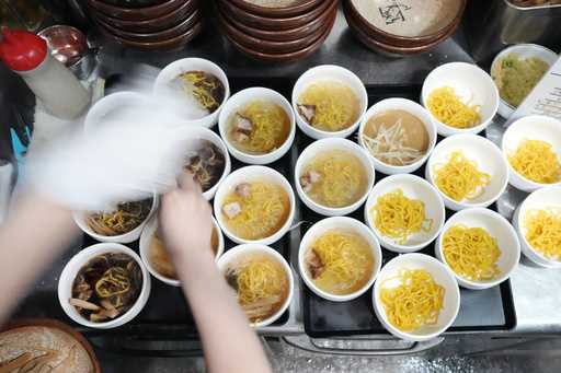 A staff member prepares small bowls of noodle for participants of Tokyo Ramen Tours at Shinbusakiya…