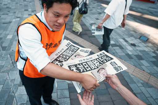 A staff member distributes an extra edition of the Yomiuri Shimbun newspaper reporting that Preside…