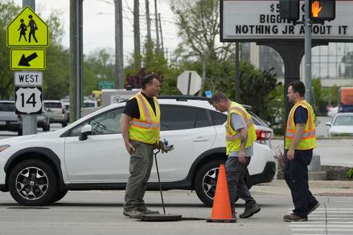 Workers surround a manhole on a street in Park Ridge, Ill