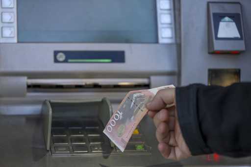 A man withdraws Serbian Dinars from a bank cash machine in northern Serb-dominated part of ethnical…