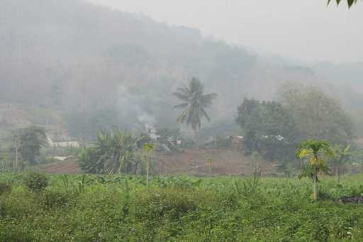 Farmers tend their fields in stifling temperatures as surrounding hills are choked by smoke from fi…
