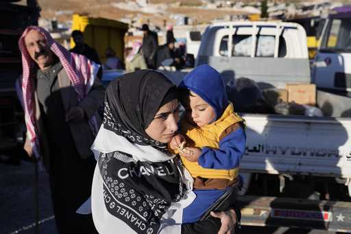 A Syrian refugee woman carries her child as she prepares to go back home to Syria as part of a volu…