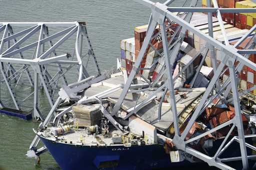 A container ship rests against wreckage of the Francis Scott Key Bridge as night falls on Tuesday, …