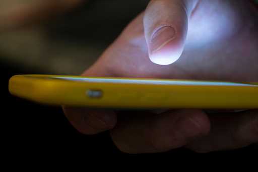 A man uses a cell phone in New Orleans on August 11, 2019. (AP Photo/Jenny Kane, File)