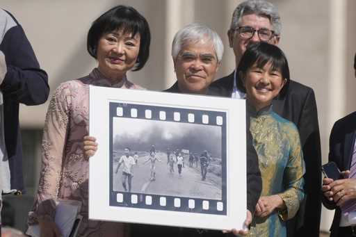 Pulitzer Prize-winning photographer Nick Ut, center, flanked by Kim Phuc, left, holds the" Napalm G…