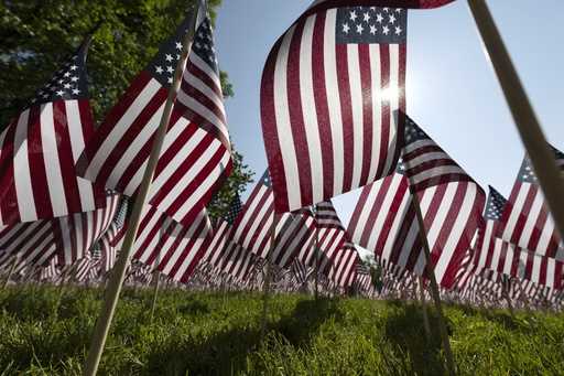 The sun shines through the flags in the Memorial Day Flag Garden on Boston Common, May 27, 2023, in…