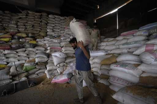 A Pakistani worker carries sacks of wheat in a warehouse in Karachi, Pakistan, on Wednesday, July 2…