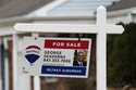 A for sale sign stands near homes in Buffalo Grove, Ill