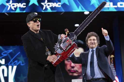 Elon Musk holds up a chainsaw he received from Argentina's President Javier Milei, right, as they a…