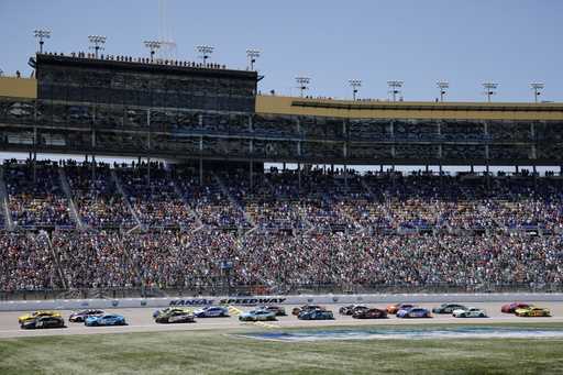Drivers head down the front straightaway at the start of a NASCAR Cup Series auto race at Kansas Sp…