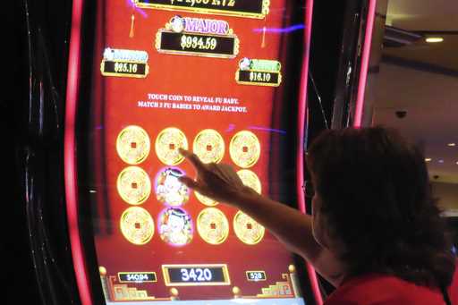 A gambler touches the screen of a slot machine at Harrah's casino in Atlantic City N