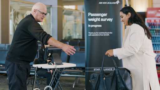 In this photo provided by Air New Zealand, a woman hands her bag to a staff member to be weighed ah…