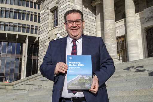 New Zealand Finance Minister Grant Robertson poses with the front cover of his Budget 2023 on the s…