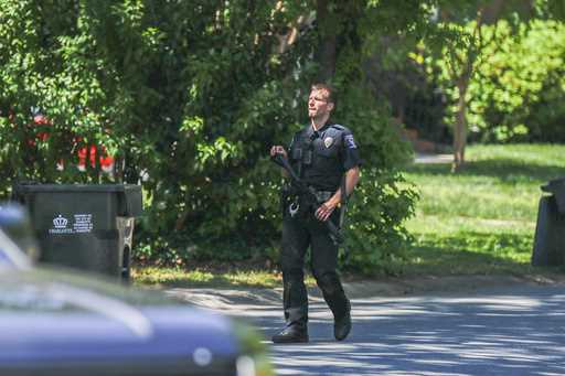 A Charlotte Mecklenburg police officer carries a gun as he walks in the neighborhood where an offic…