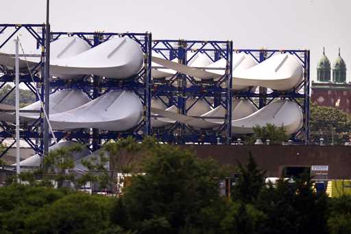 Giant wind turbine blades for the Vineyard Winds project are stacked on racks in the harbor, July 1…