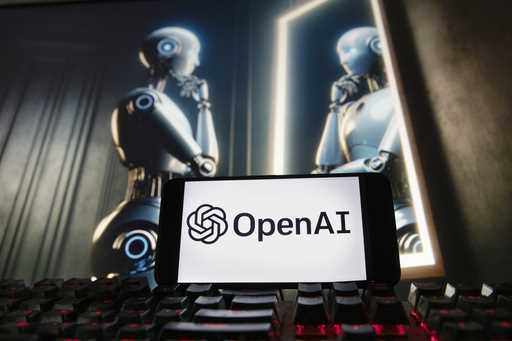 FILE- The OpenAI logo is displayed on a cell phone with an image on a computer monitor generated by…