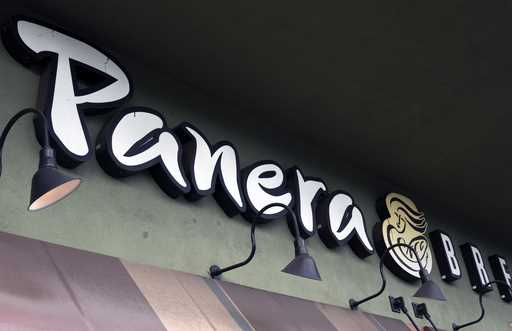 A Panera Bread sign and logo is attached to the outside of a Panera Bread restaurant location in th…