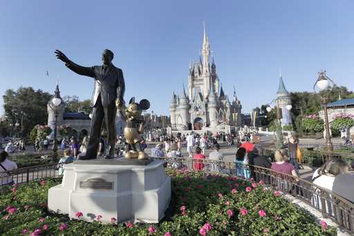 A statue of Walt Disney and Mickey Mouse appears in front of the Cinderella Castle at the Magic Kin…