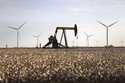 A pump jack and wind turbines stand inside of a cotton field on October 18, 2015, near Lamesa, Texa…