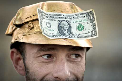 A man wears a one dollar bill on a miner's helmet painted in gold color in Bucharest, Romania, Sept…