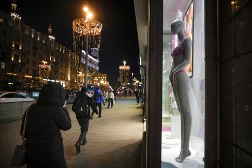 Pedestrians walk past a mannequin in a window of a fashion store in Tverskaya street in Moscow, Rus…