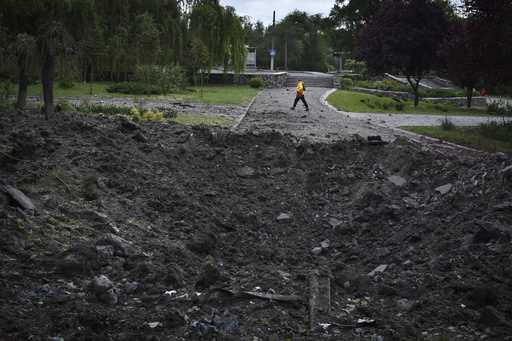 A woman walks in front of a crater caused by a Russian missile attack in Zaporizhzhia, Ukraine, Wed…