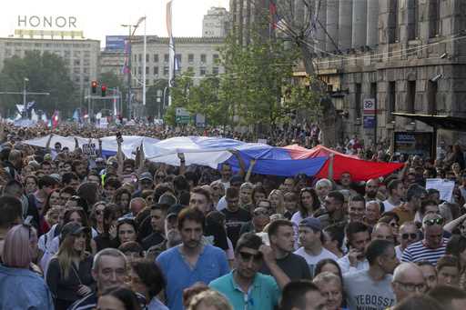 People hoist a Serbian flag as they walk down a street during an anti-government protest in Belgrad…