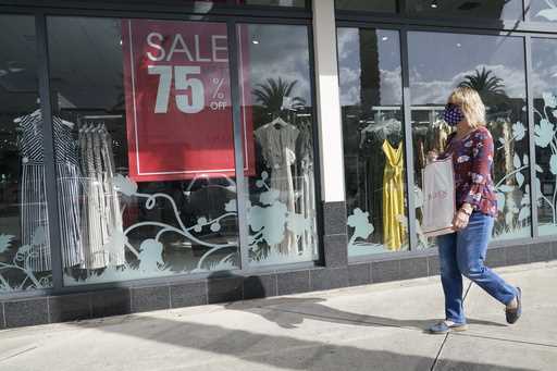 File - A shopper walks by a store, November 18, 2020 in Pembroke Pines, Fla