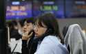 A currency trader watches monitors at the foreign exchange dealing room of the KEB Hana Bank headqu…