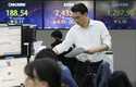 A currency trader works near the screens showing the Korea Composite Stock Price Index…