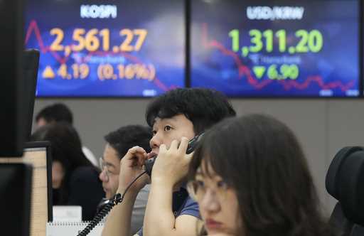 A currency stretches near the screens showing the Korea Composite Stock Price Index…