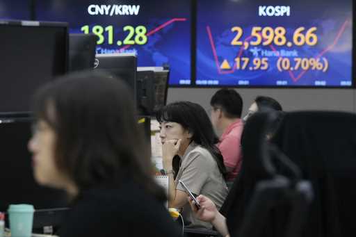 A currency trader watches monitors near the screens showing the Korea Composite Stock Price Index…