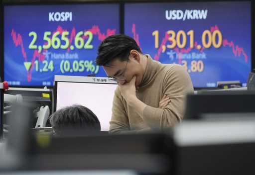 A currency trader gestures at the foreign exchange dealing room of the KEB Hana Bank headquarters i…
