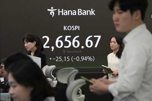 Currency traders work near the screen showing the Korea Composite Stock Price Index…