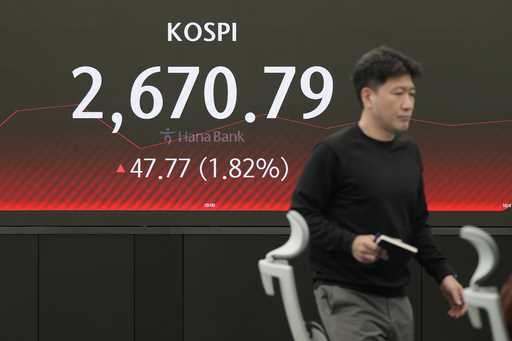 A currency traders walks near the screen showing the Korea Composite Stock Price Index…