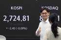 A currency trader gives a thumps up near the screen showing the Korea Composite Stock Price Index…