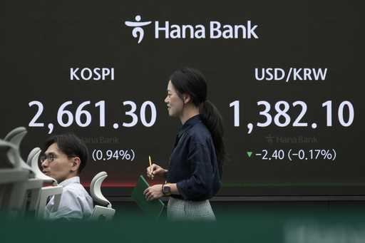 Currency traders work near the screen showing the Korea Composite Stock Price Index…