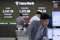 A currency trader watches monitors near a screen showing the Korea Composite Stock Price Index…