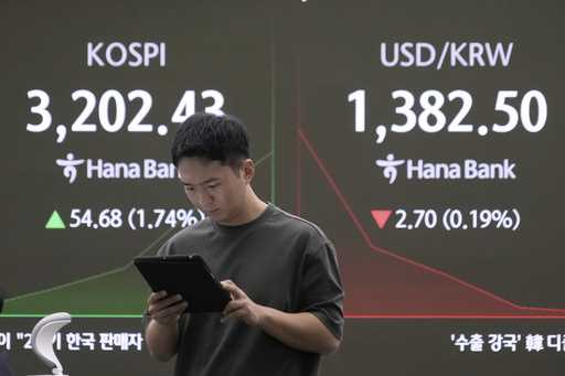 A currency trader works near a screen showing the Korea Composite Stock Price Index…