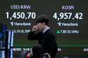 Currency traders watch monitors near a screen showing the Korea Composite Stock Price Index…