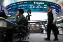 A currency trader talks on the phone near a screen showing the Korea Composite Stock Price Index…