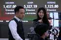 Currency traders work near a screen showing the Korea Composite Stock Price Index…
